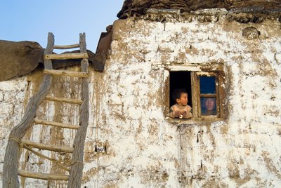 Young boy and mother in window of traditional Zanskari village house, roof ladder, Reru by Unbekannt Unbekannt
